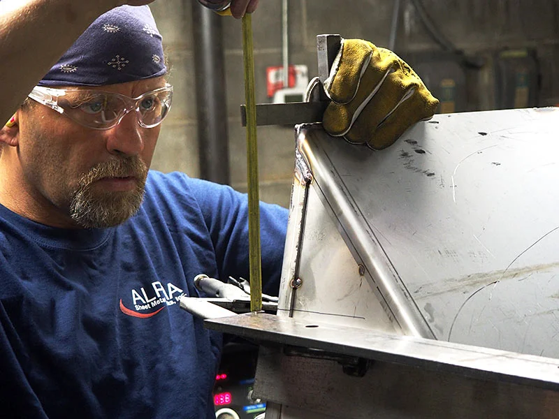 Alpha employee welding a sheet-metal component